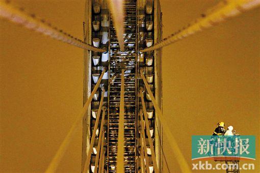 截至今日零時(shí)，男子仍未有下橋舉動。圖為公安和消防人員乘消防云梯在高空上和男子交談。